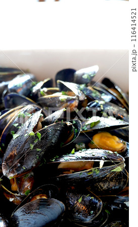 Closeup Steamed Mussels in white wine, herbs and lemon on white bow 116414521