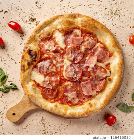 Round, cooked pizza with pepperoni and ham 116416030