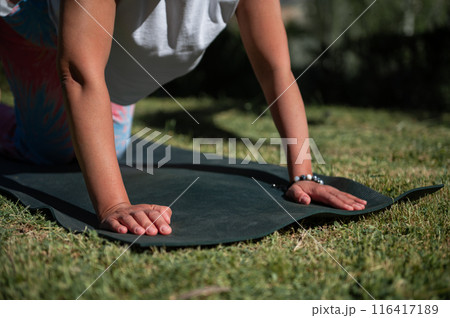 Outdoor yoga practice with person on mat performing exercise in sunny garden setting Outdoor yoga practice with person on mat performing exercise in sunny garden setting 116417189