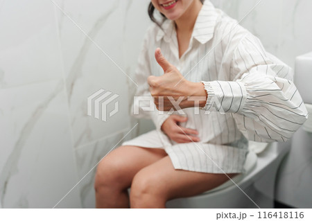 happy woman giving a thumbs up from a toilet bowl in bathroom 116418116