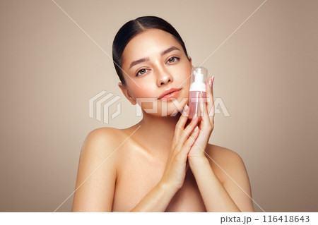 Young woman shows off a bottle with a foam dispenser for washing Young woman shows off a bottle with a foam dispenser for washing 116418643
