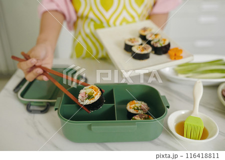 Woman Putting Kimbap In Lunchbox Woman Putting Kimbap In Lunchbox 116418811