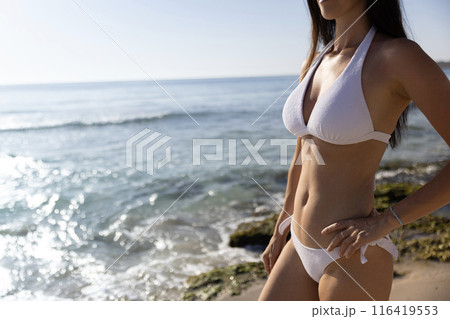 Pretty young sexy woman in bikini posing on a beach in summer on tropic island paradise 116419553