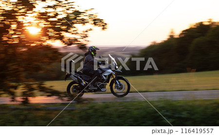 Driver riding motorcycle on empty road during sunset 116419557
