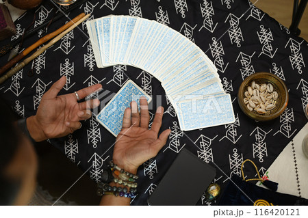 Overhead view of fortune teller spreading tarot cards on a table. Forecasting and divination concept Overhead view of fortune teller spreading tarot cards on a table. Forecasting and divination concept 116420121