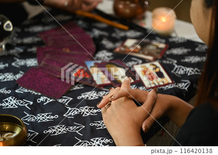 Cropped shot fortune teller reading tarot cards and predicting the future of young woman visitor Cropped shot fortune teller reading tarot cards and predicting the future of young woman visitor 116420138