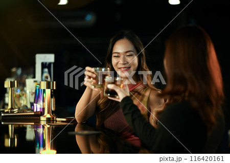 Happy female friends celebrating holiday, toasting with drinks at the bar counter. Celebrations and friendship concept 116420161