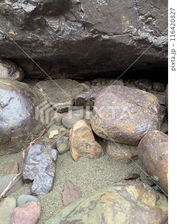 Small pebbles and a large rock on the beach with a smooth surface and interesting shapes 116420827