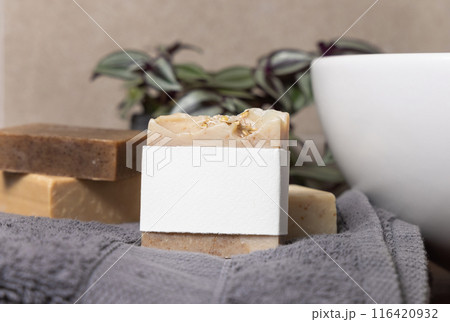 Soap bar with blank label near grey towels, plant and basin on wood in bathroom, mockup Soap bar with blank label near grey towels, plant and basin on wood in bathroom, mockup 116420932