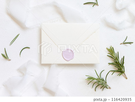 Blank sealed envelope near white silk ribbons and rosemary leaves top view, wedding mockup Blank sealed envelope near white silk ribbons and rosemary leaves top view, wedding mockup 116420935