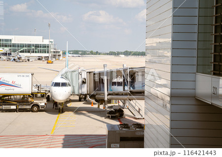 A commercial airplane is parked at airport gate, while passengers are boarding 116421443