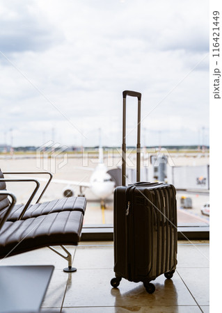 Waiting area at the airport with luggage and an airplane in the background Waiting area at the airport with luggage and an airplane in the background 116421449