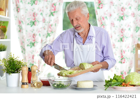 Happy retired senior man cooking in kitchen. Happy retired senior man cooking in kitchen. 116422421
