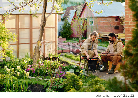 Mature farmers sitting by barrel smoker 116423312