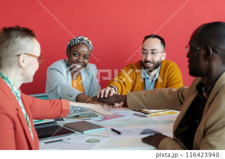 Diverse Team Celebrating Success with Hands Stacked in Office 116423948
