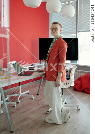 Portrait Of Businesswoman Standing By Desk With Laptop In Office 116424241