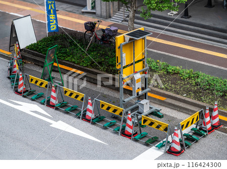 交差点近くの車道で工事中の囲いが設置されている風景 交差点近くの車道で工事中の囲いが設置されている風景 116424300