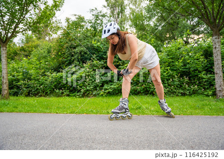 Roller skater woman warming up in park before rollerblading on inline skates. Outdoor activities. Summer roller skating. 116425192