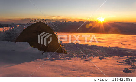 Lone tent on snowy Mount Elbrus at sunrise, climber solo travels in extreme winter conditions, explores alpine landscape amid snow storm, adventure, challenge 116425888