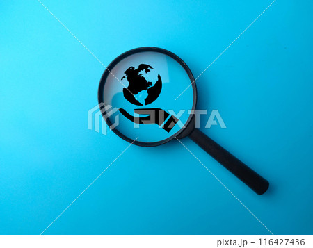 World wild concept.Magnifying glass with hand holding world icon on a blue background 116427436
