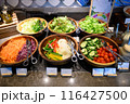Several salad dishes were placed on the buffet line. 116427500
