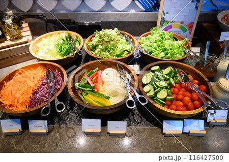 Several salad dishes were placed on the buffet line. 116427500