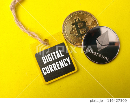 Top view golden bitcoin ,silver ethereum and colored board with text DIGITAL CURRENCY on yellow background. 116427509