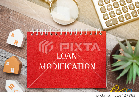 Loan modification concept - change made to the terms of an existing loan by a lender. Business and finance concept. Inscription on a notepad, miniature houses and a magnifying glass 116427863