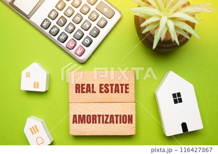 Real estate amortization concept - process of gradually paying off a mortgage or loan over a set period through regular, equal payments. Wooden blocks, houses and calculator Real estate amortization concept - process of gradually paying off a mortgage or loan over a set period through regular, equal payments. Wooden blocks, houses and calculator 116427867