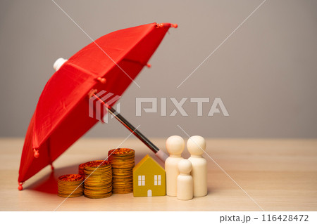 Property and family insurance concept. Miniature figures of a family stand near a house with coins under a red umbrella. Safety life 116428472