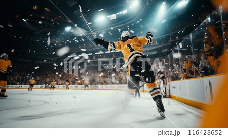 Ecstatic hockey player celebrating a goal with arms raised in a packed arena. 116428652