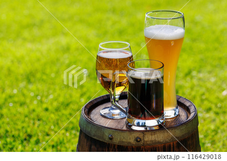 Variety of beer glasses on rustic wooden barrel 116429018