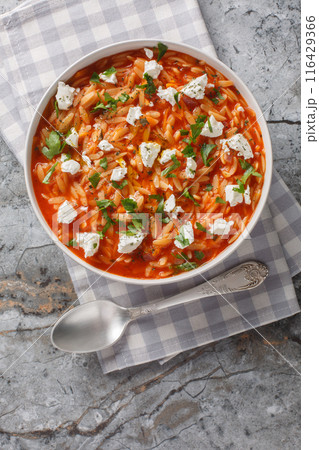 Greek pasta kritharaki or orzo with tomato sauce, feta, onion and herbs closeup on the plate. Vertical top view 116429366