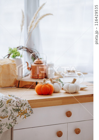 Bright kitchen with wooden furniture with kitchen utensils and three decorative pumpkins. Bright kitchen with wooden furniture with kitchen utensils and three decorative pumpkins. 116429535