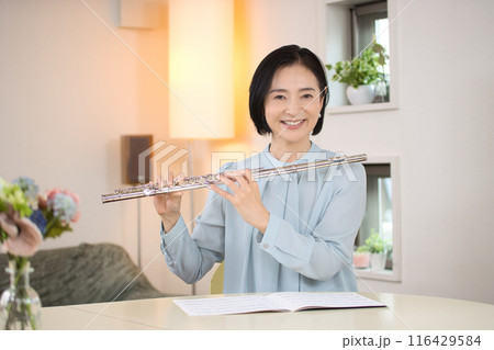 リビングでフルートを吹くミドル女性 116429584