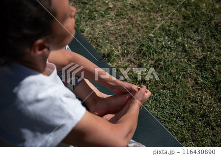 Woman practicing yoga outdoors on a sunny day, focused on meditation and relaxation 116430890