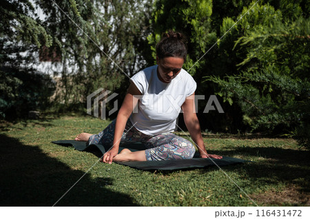 Woman practicing yoga in a serene garden setting on a sunny day 116431472