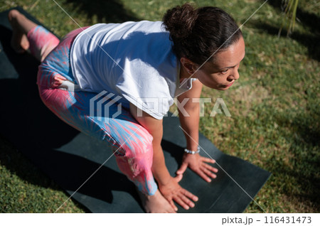 Woman practicing outdoor yoga exercise on a mat in a park Woman practicing outdoor yoga exercise on a mat in a park 116431473
