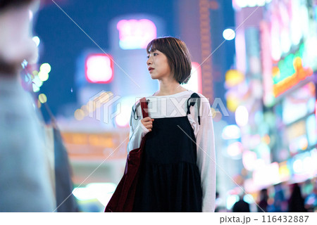 夜の繁華街を見つめる若い女性 116432887