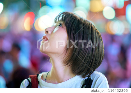夜の繁華街を見つめる若い女性 116432896