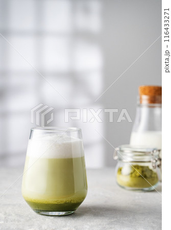 Green matcha latte in a glass on a gray background with morning shadows from the window 116433271