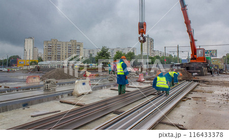 Orange construction telescopic crane unloading tram rails from truck timelapse. Orange construction telescopic crane unloading tram rails from truck timelapse. 116433378