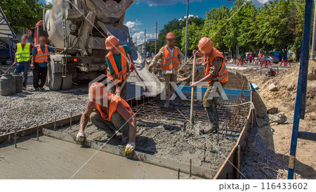 Concrete leveling works for road construction with many workers and mixer timelapse 116433602