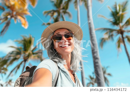 Woman in hat and sunglasses taking selfie on beach 116434172