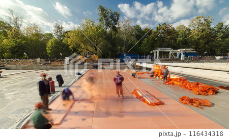 Construction workers and builders laying insulating underlayment at a new metro station construction site timelapse. Construction workers and builders laying insulating underlayment at a new metro station construction site timelapse. 116434318