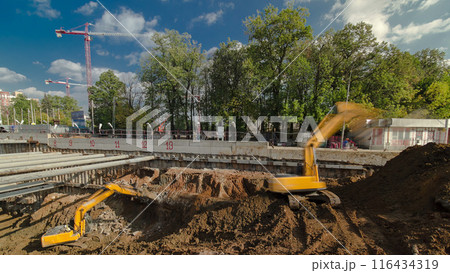 Yellow excavator and jackhammer machine on a construction site timelapse 116434319