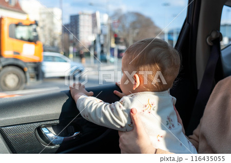 A child plays in a car and looks out the window with interest. Concept of unsafe transportation of children A child plays in a car and looks out the window with interest. Concept of unsafe transportation of children 116435055
