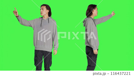 Person indicating left or right directions on camera, pointing to both sides and recommending another path. Asian young man advising someone to go that way, greenscreen backdrop. Person indicating left or right directions on camera, pointing to both sides and recommending another path. Asian young man advising someone to go that way, greenscreen backdrop. 116437221