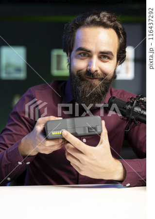 Tech expert filming technology review of newly released V mount battery, presenting features to audience. Reviewer showcasing charging device specs to interested subscribers 116437292