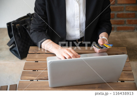 Cropped shot view of business woman holding credit card during using laptop for online shopping. Cropped shot view of business woman holding credit card during using laptop for online shopping. 116438913